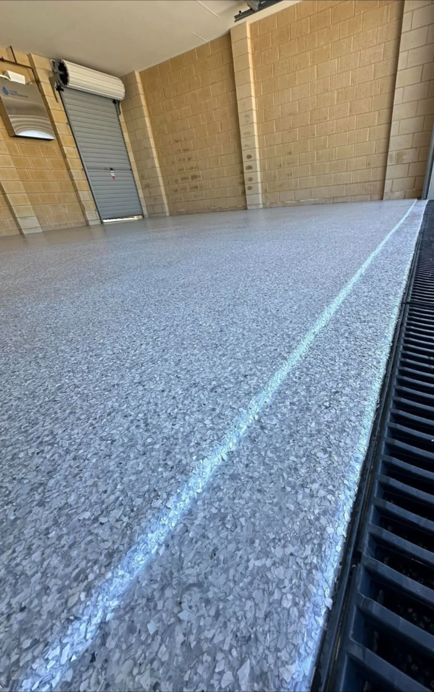 Close-up of a grey flake epoxy garage floor beside a trench drain
